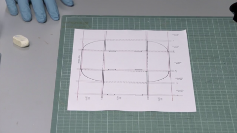 A template for the base of a box with the measurements drawn on in pencil.