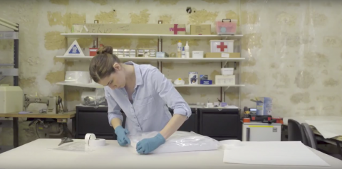 Caption: Iva demonstrates sealing the plastic bag with packing tape. Iva has rolled one side of the plastic bag with large sealing tape.