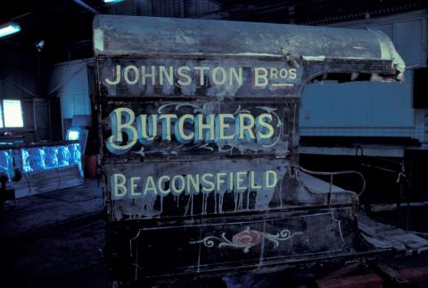"A butcher's cart in poor condition with "Johnston Bros Butchers Beaconsfield" written on the side."